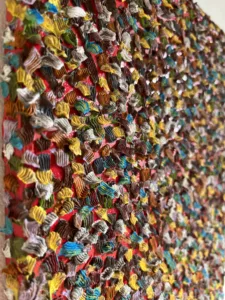 Gum Wall Tactile Textured Squeeze — abstract oil-and-wax painting; hundreds of piped impasto dabs in yellow, blue, white, green and brown covering a red ground — detail 1 of 3, close-up of surface texture