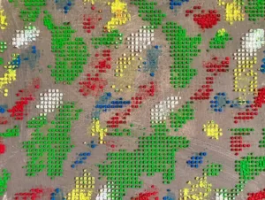 Physical Pixel Abstract Pattern Composition In Blue Green Red White And Yellow — abstract oil-and-wax painting; raised square dots of green, red, yellow, blue and white forming a pixel pattern on a warm gray ground — detail 3 of 3, close-up of surface texture