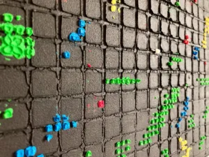 Physical Pixel Abstraction In Green Red White And Yellow On Black Background — painting; structured on a grid — detail 1 of 3, close-up of surface texture