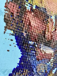 Physical Pixel Portrait Of A Man Smiling On Blue Background — grid-based oil-and-wax portrait; a smiling man built from raised square pixels of brown, pink and yellow paint on pale blue — detail 1 of 2, close-up of surface texture