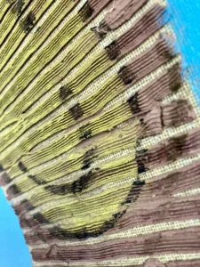Tactile Texture Linear Squeeze Portrait Smiley Face — oil-and-wax relief portrait; a brown striped head with a flat yellow smiley face, on turquoise — detail 1 of 3, close-up of surface texture