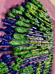 Tactile Textured Squeeze Portrait In Blue And Green On Pink Background — oil-and-wax relief portrait; a head scanned in horizontal blue lines with green and chartreuse highlights on a pink ground — detail 2 of 2, close-up of surface texture